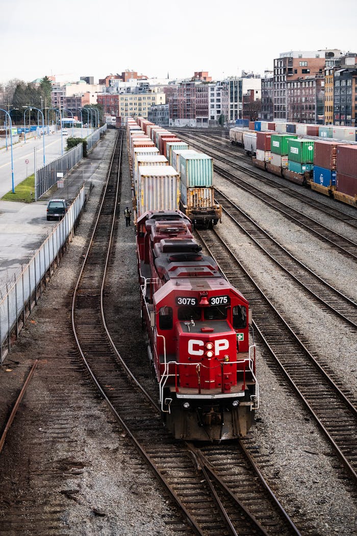 gallery-2 A red freight train with containers at a rail yard in Vancouver, showcasing industrial transportation.
